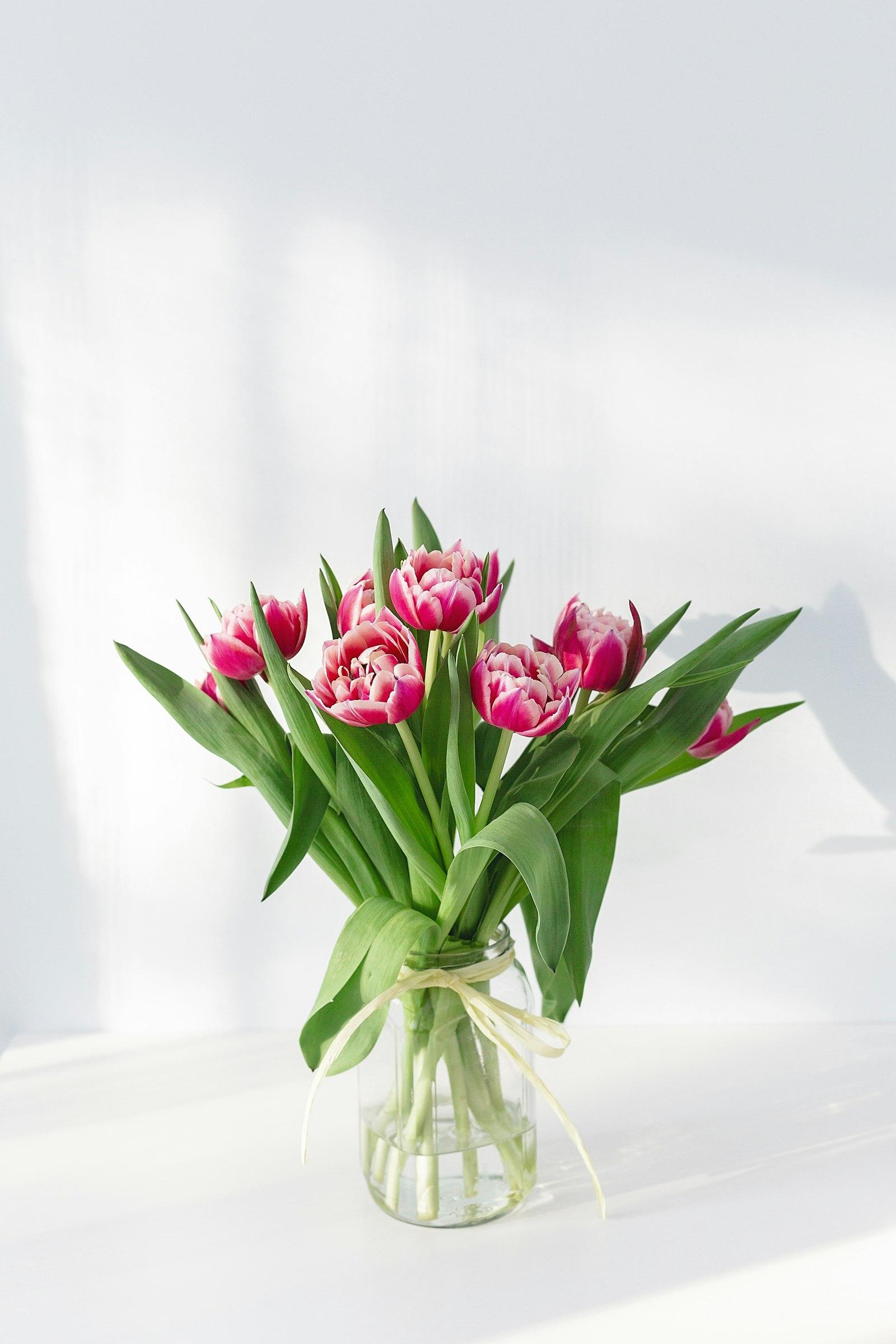Colorful birthday bouquet of pink garden roses, gerbera daisies, alstroemeria, and seasonal greenery in a clear glass vase ready for same-day delivery from a Sedalia, MO florist