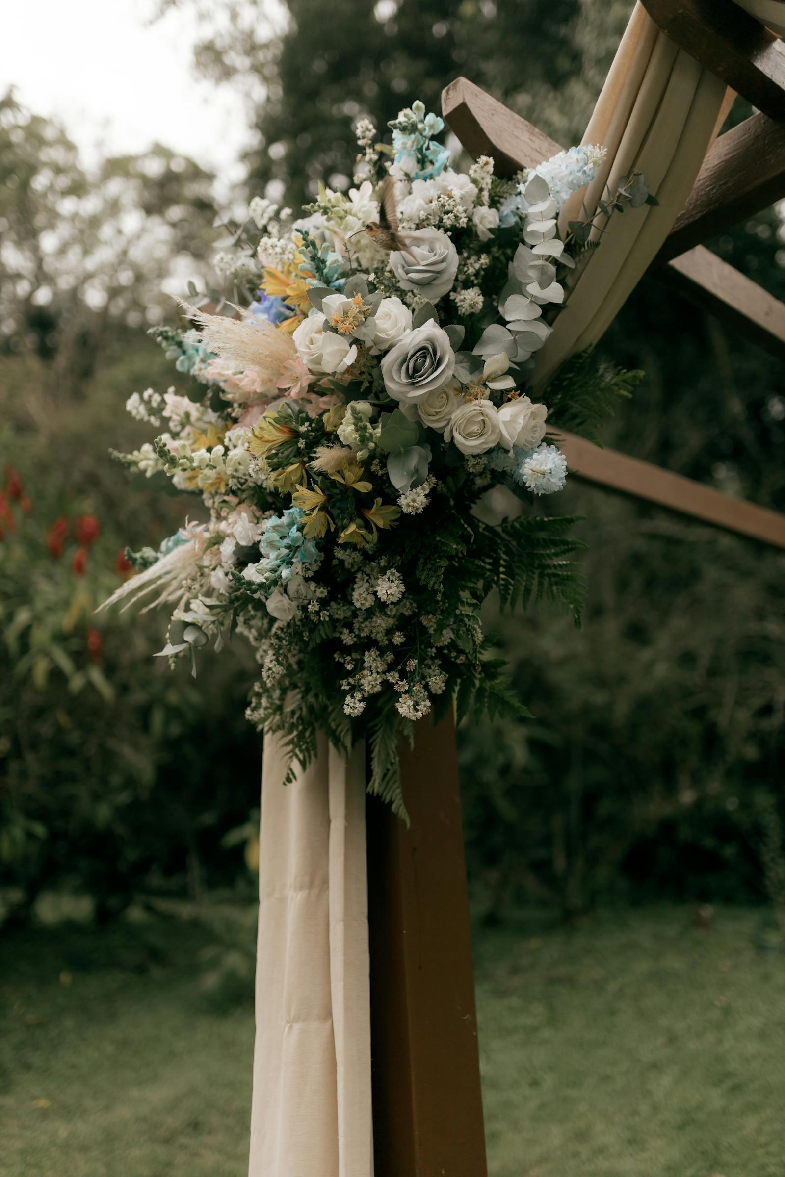 Lush floral arch with garden roses and trailing greenery set up for a Sedalia, MO wedding ceremony at an outdoor Pettis County venue