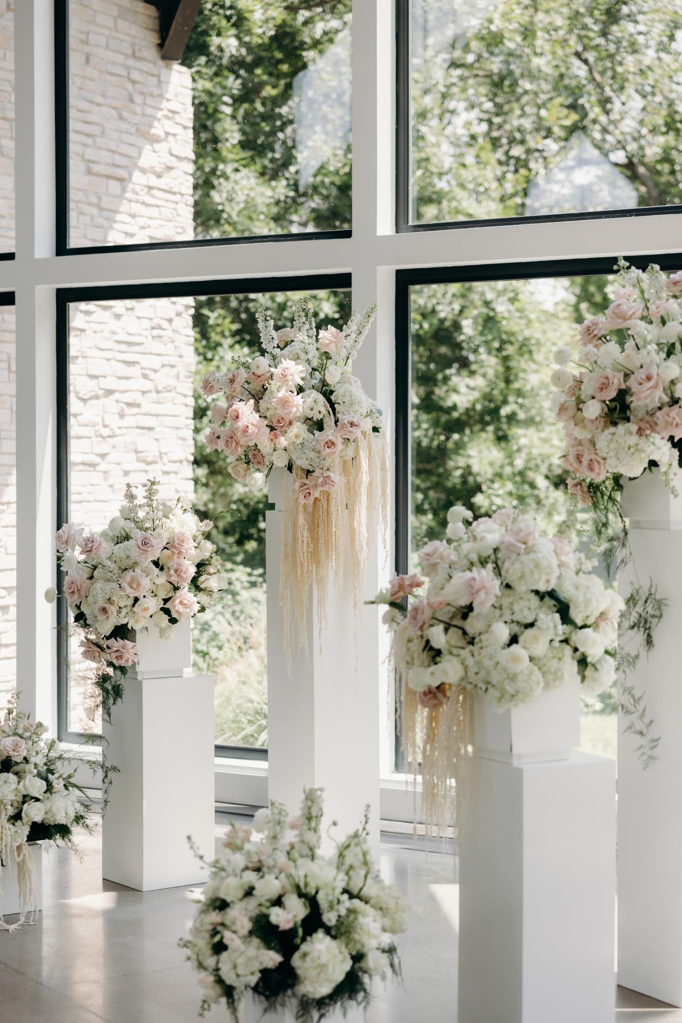 Pedestal arrangements with hanging amaranthus against black-frame windows