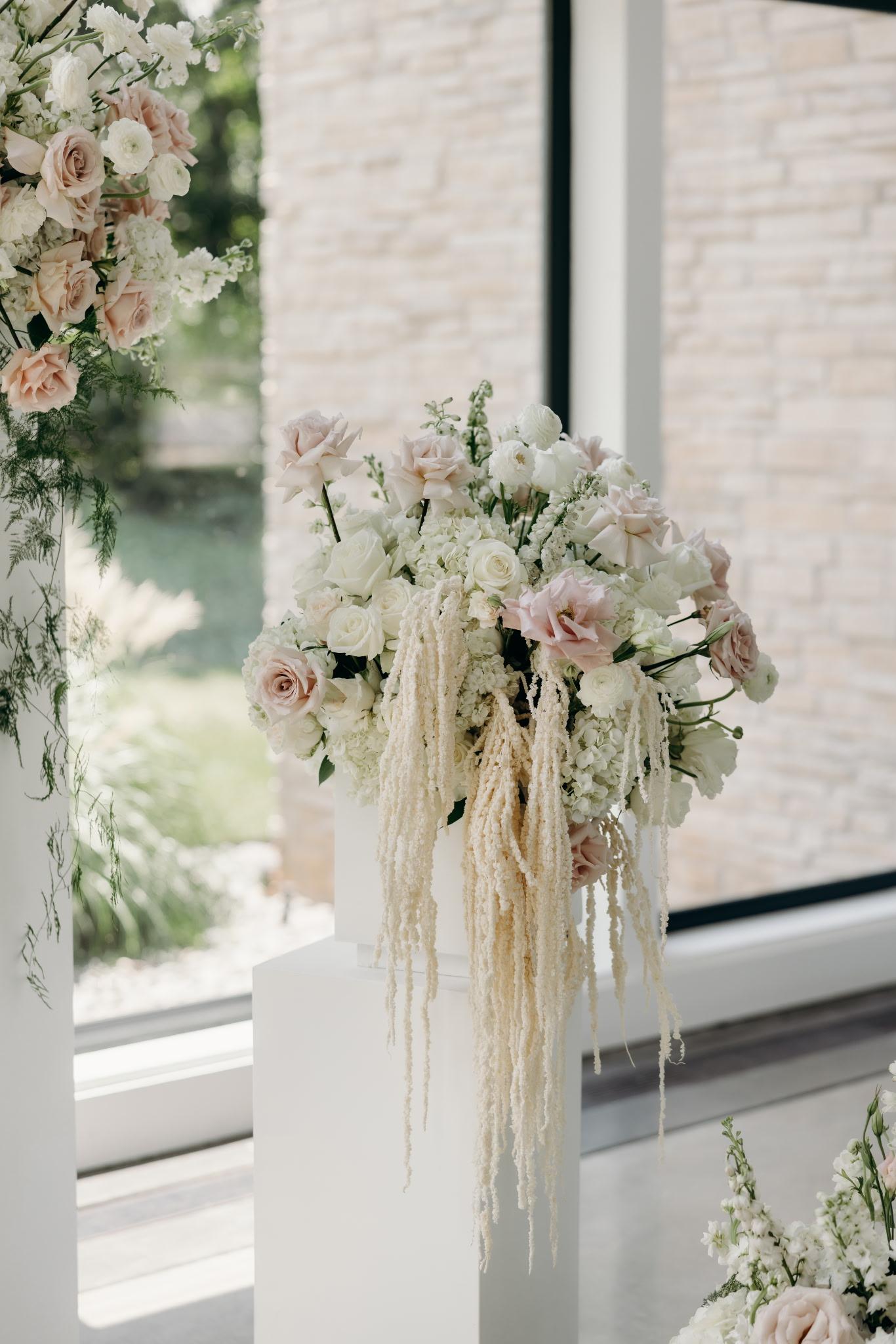 Close-up of a pedestal arrangement with roses, hydrangea, and amaranthus