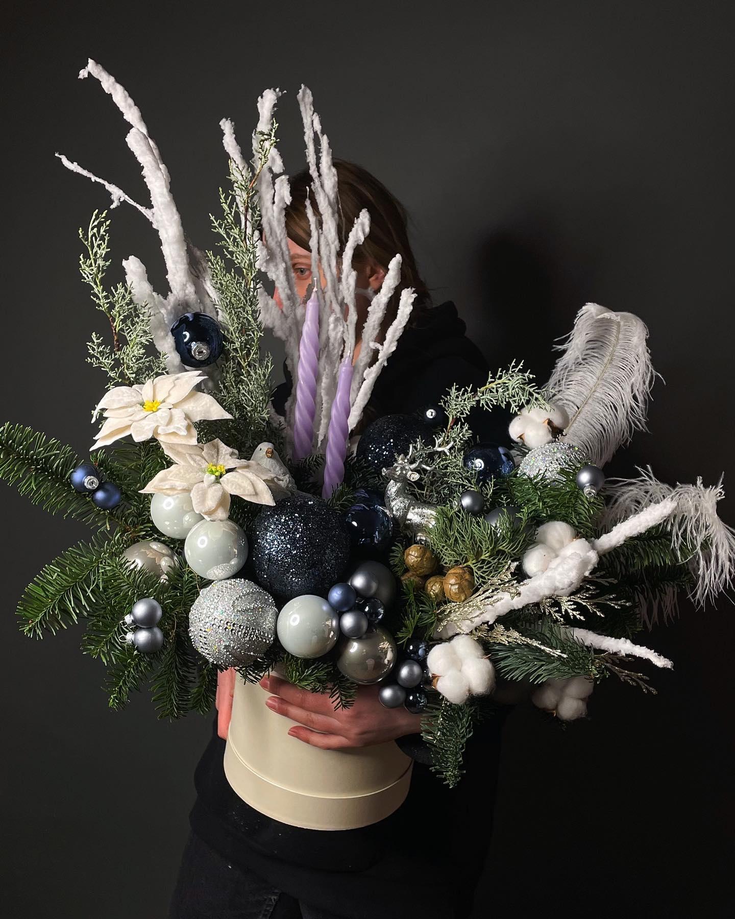 Winter holiday arrangement with white poinsettia, blue ornaments, cotton bolls, and silver accents in hat box