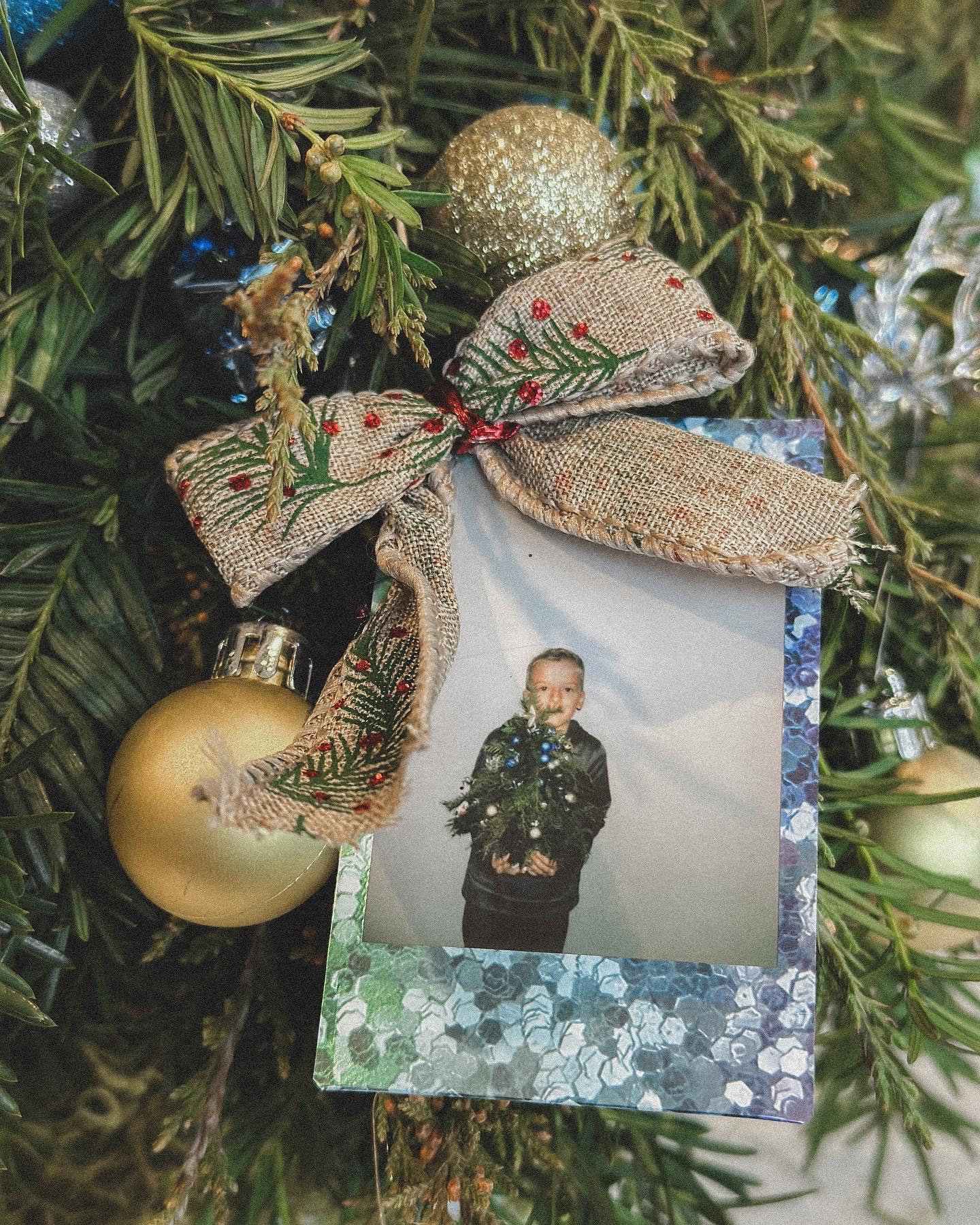 Hands adding gold and silver baubles to fresh evergreen wreath at holiday crafting event