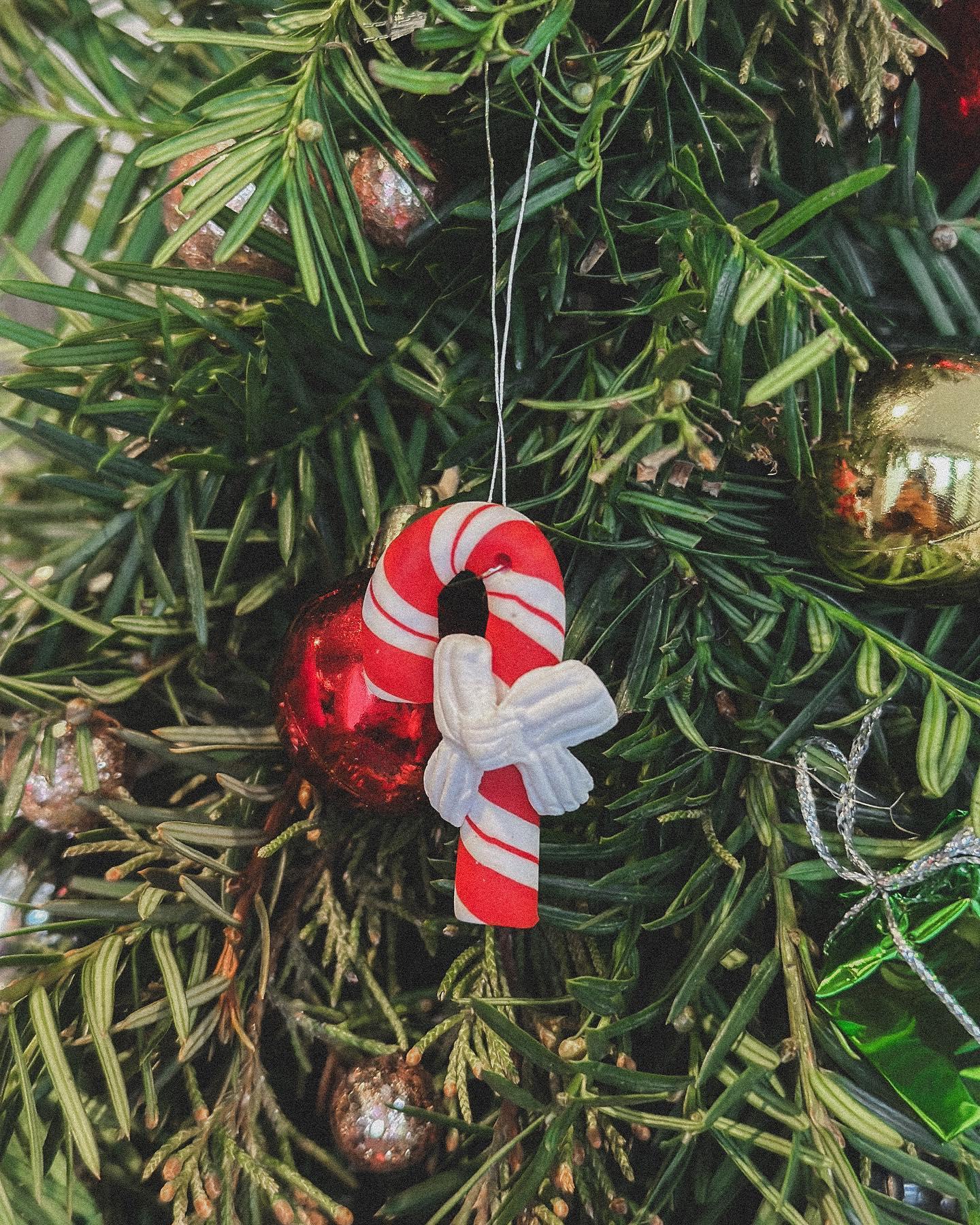 Child holding completed Christmas wreath decorated with red and gold ornaments