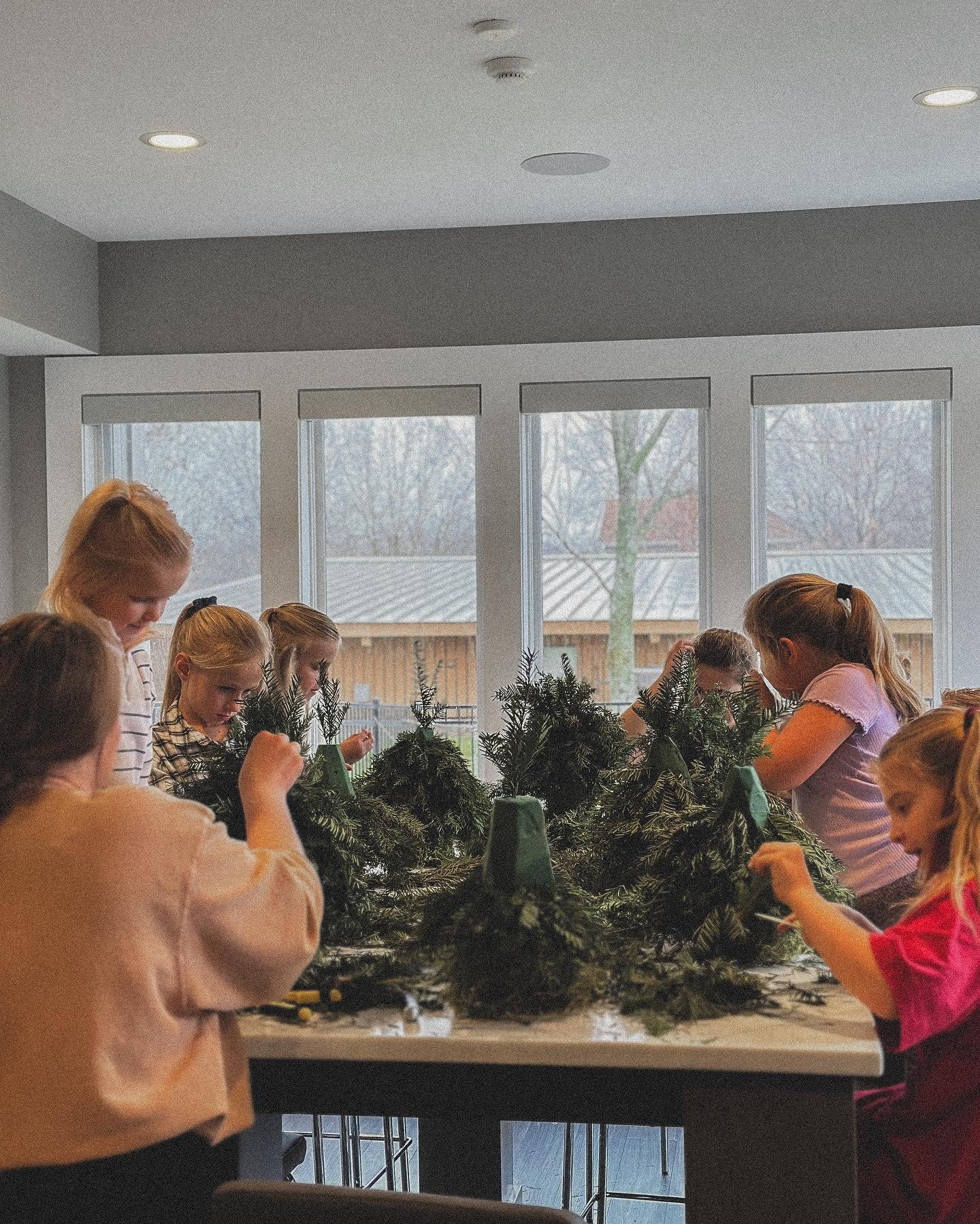 Group of children creating evergreen arrangements at kids floral design workshop in Sedalia