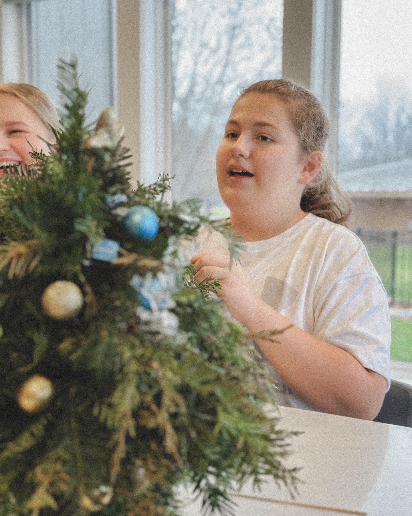 Completed holiday mini-trees and arrangements from kids floral workshop displayed on table