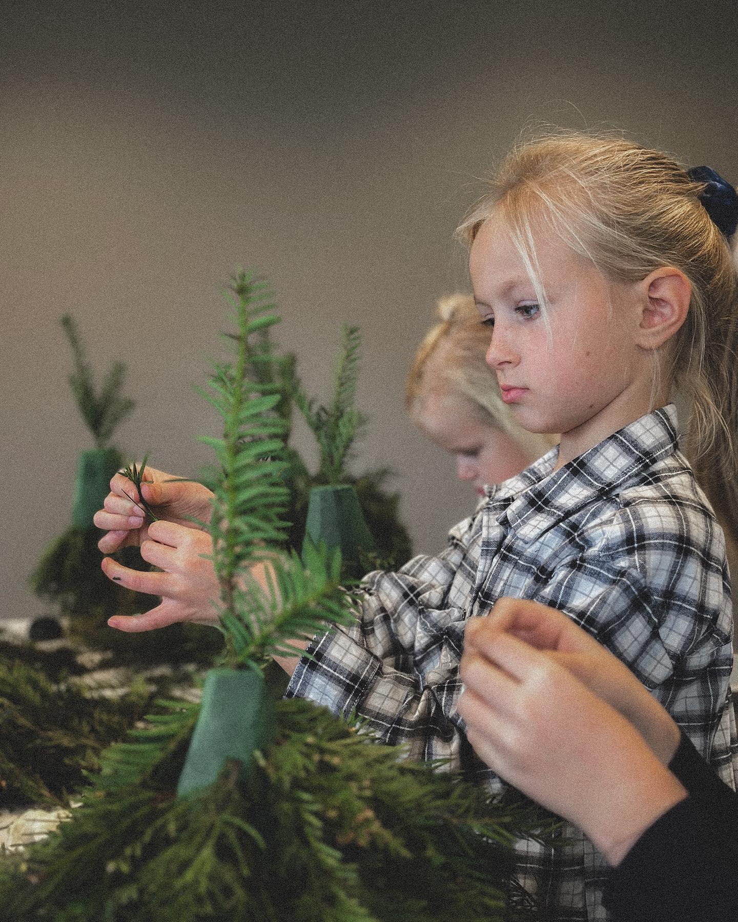 Instructor helping children with holiday floral arrangements at Sedalia Flowers workshop event