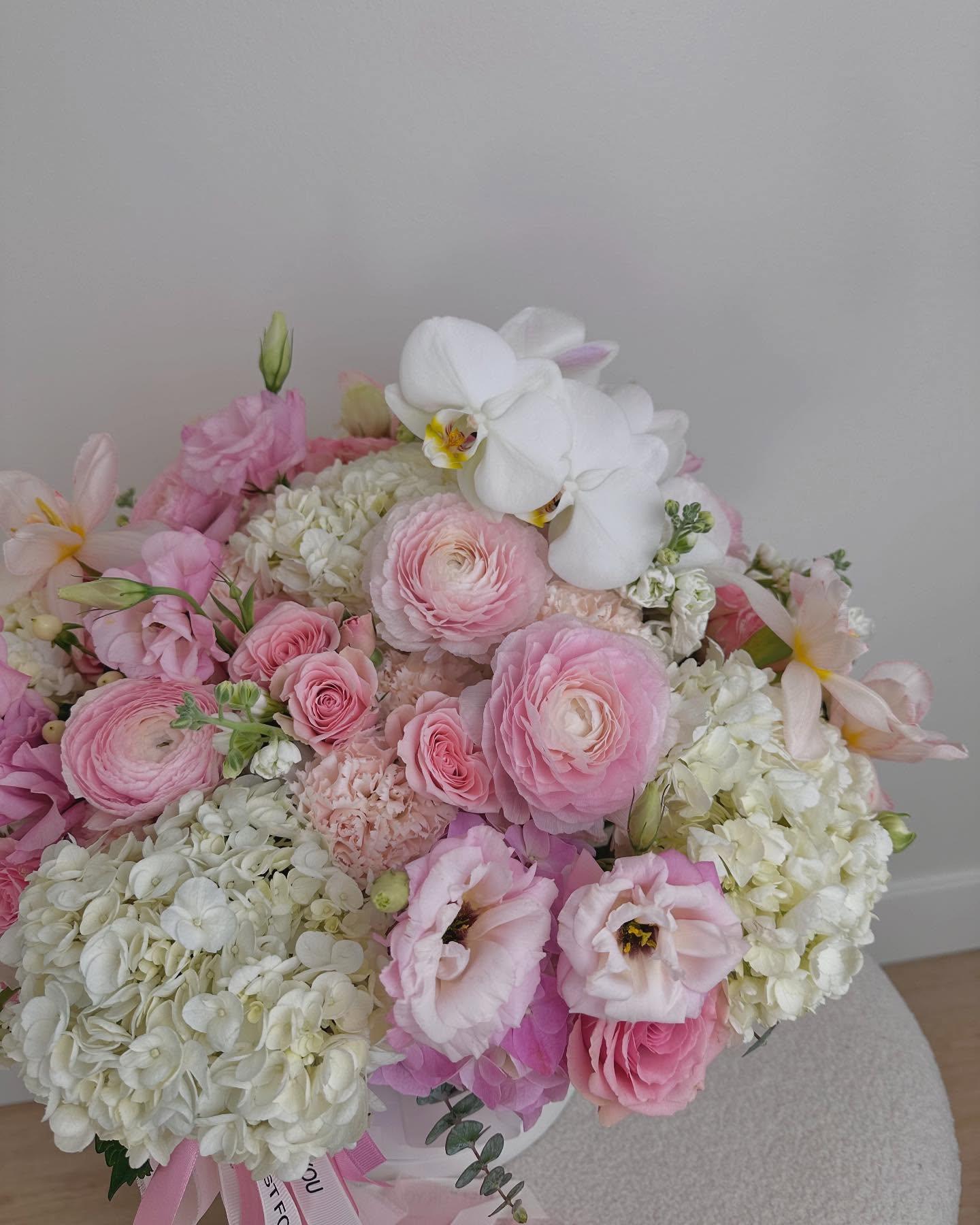 Colorful luxury flower basket with purple anemones, blue hydrangea, orange roses, daffodils, and pampas grass