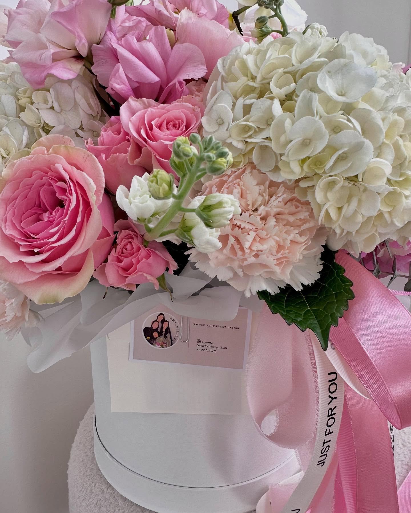 Close-up of overflowing spring basket with pampas grass, orange garden roses, blue hydrangea, and purple anemones