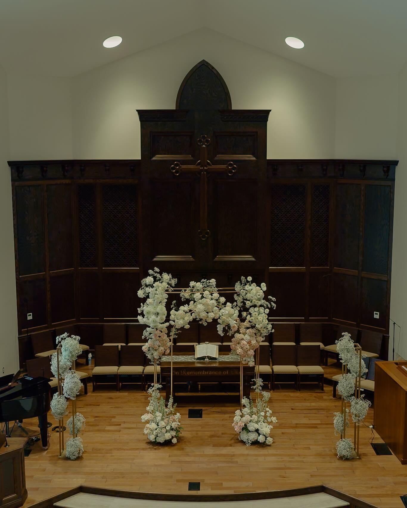 Full church altar decorated with white and blush floral arch, baby's breath columns, and ceremony flowers